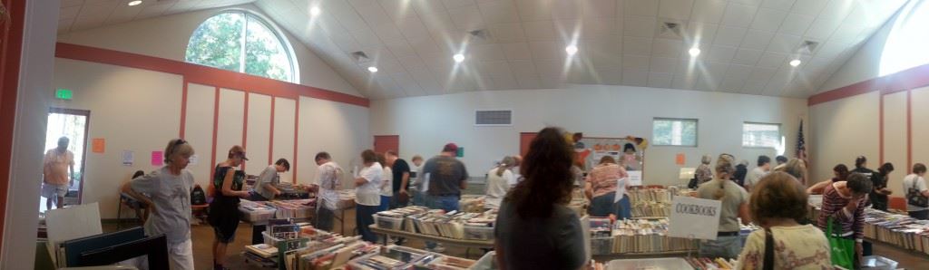 Many people inside a well lit room talking among themselves